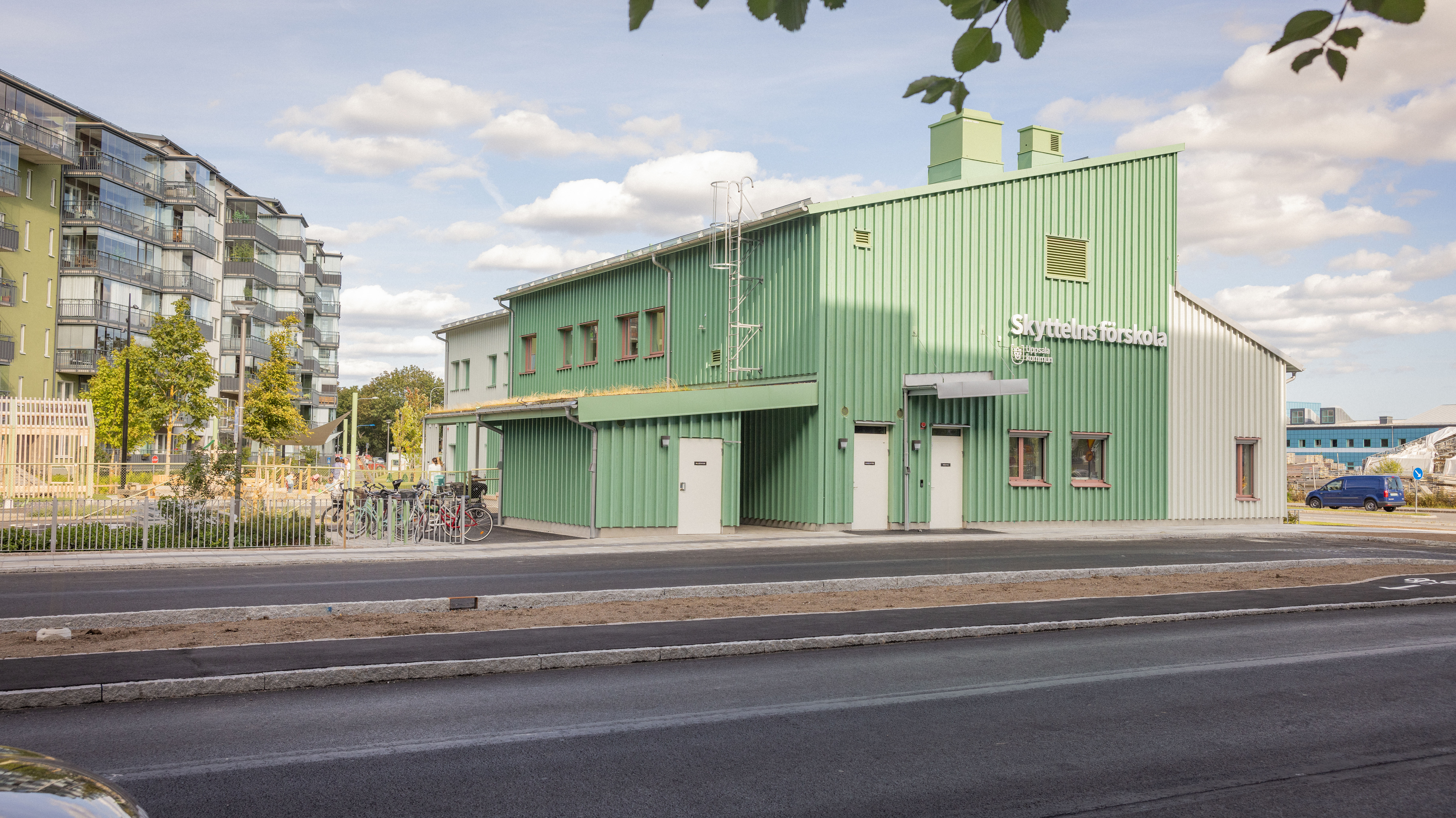 Nybyggd förskola i turkos färg och väg i förgrunden.